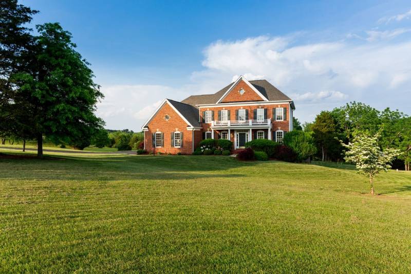 A large brick house sitting on top of a lush green field.