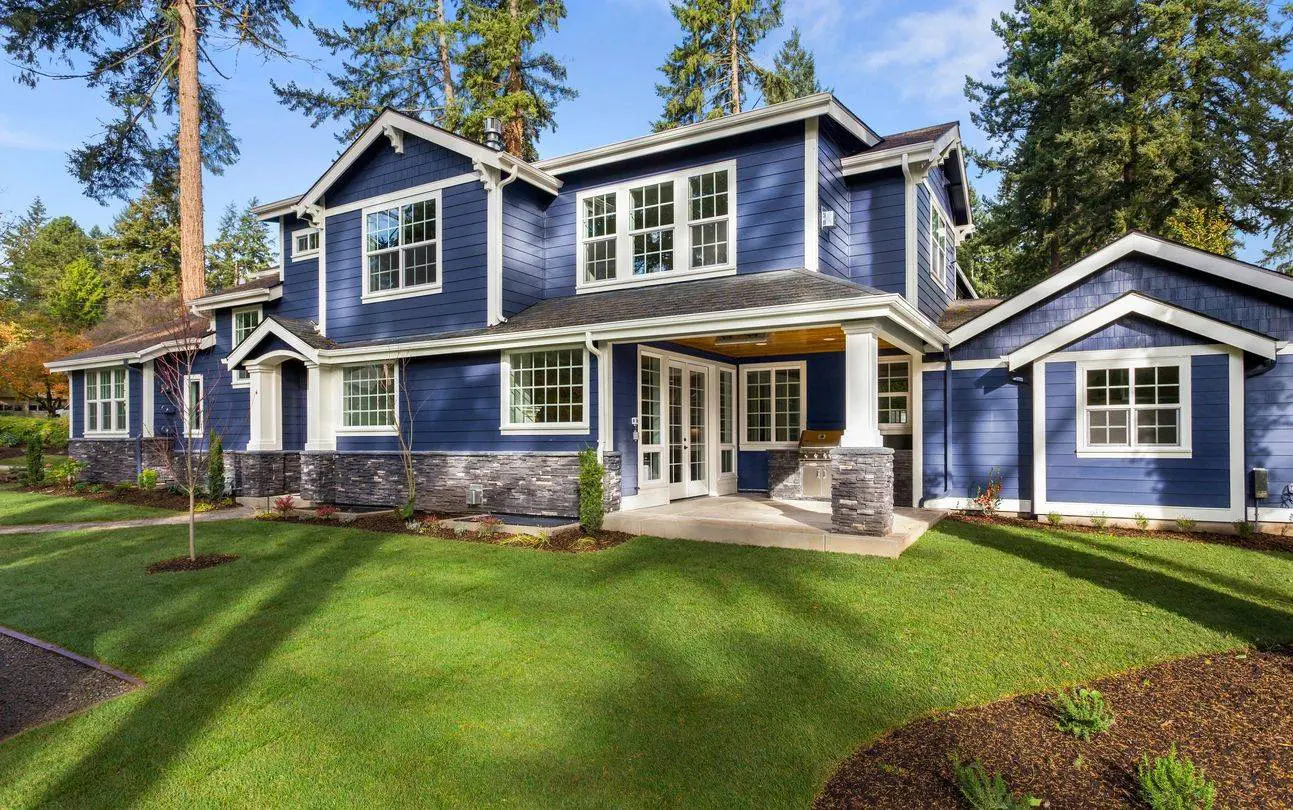 A blue house with white trim and green grass.